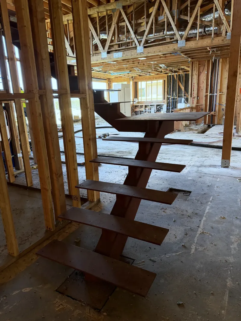 A steel stringer staircase with folded treads inside the timber frame