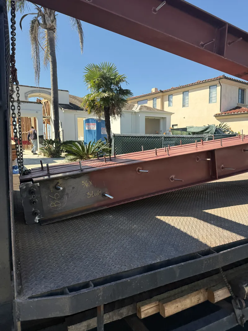 A structural steel beam arriving on a flatbed at the jobsite